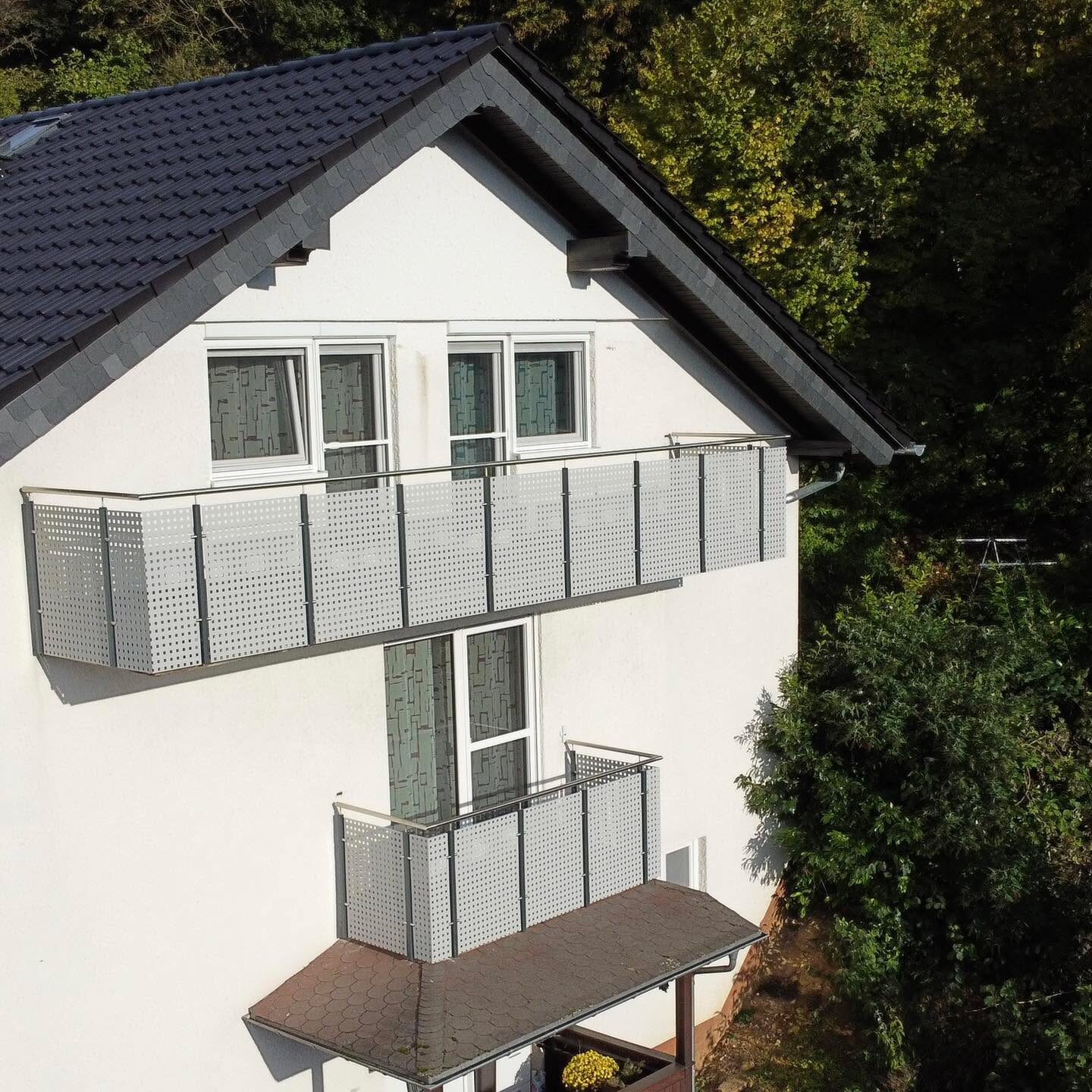 Zwei übereinanderliegende Balkone mit Lochblechfüllung an einem Wohnhaus
