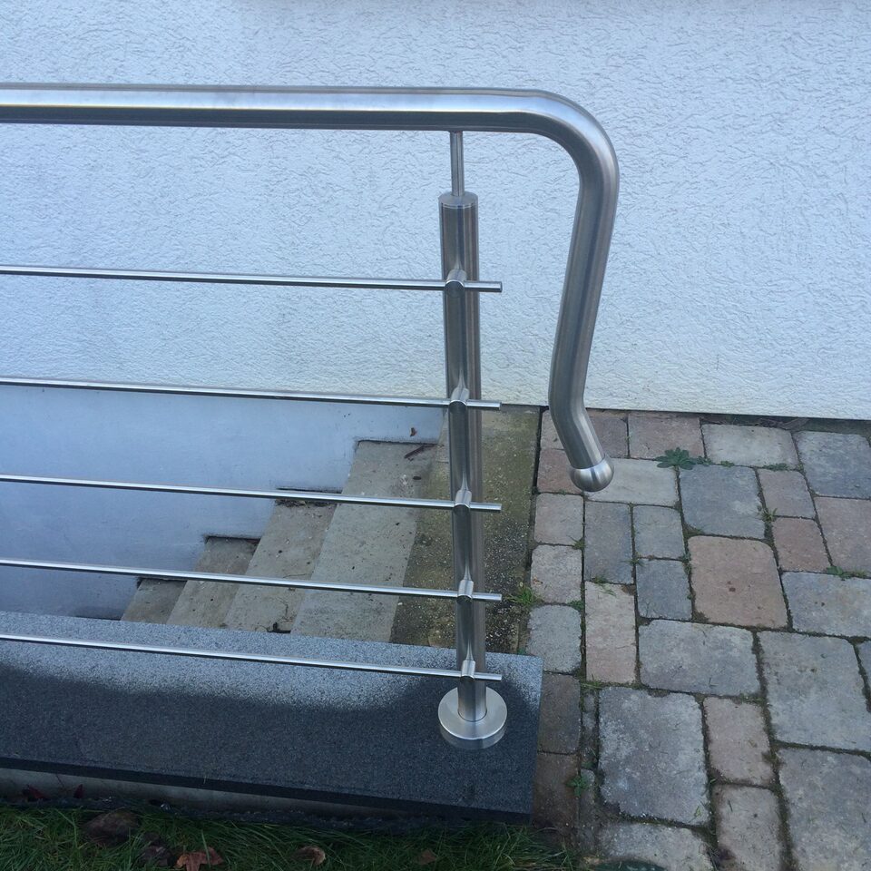 Gebogener Edelstahlhandlauf am Ende einer Außentreppe