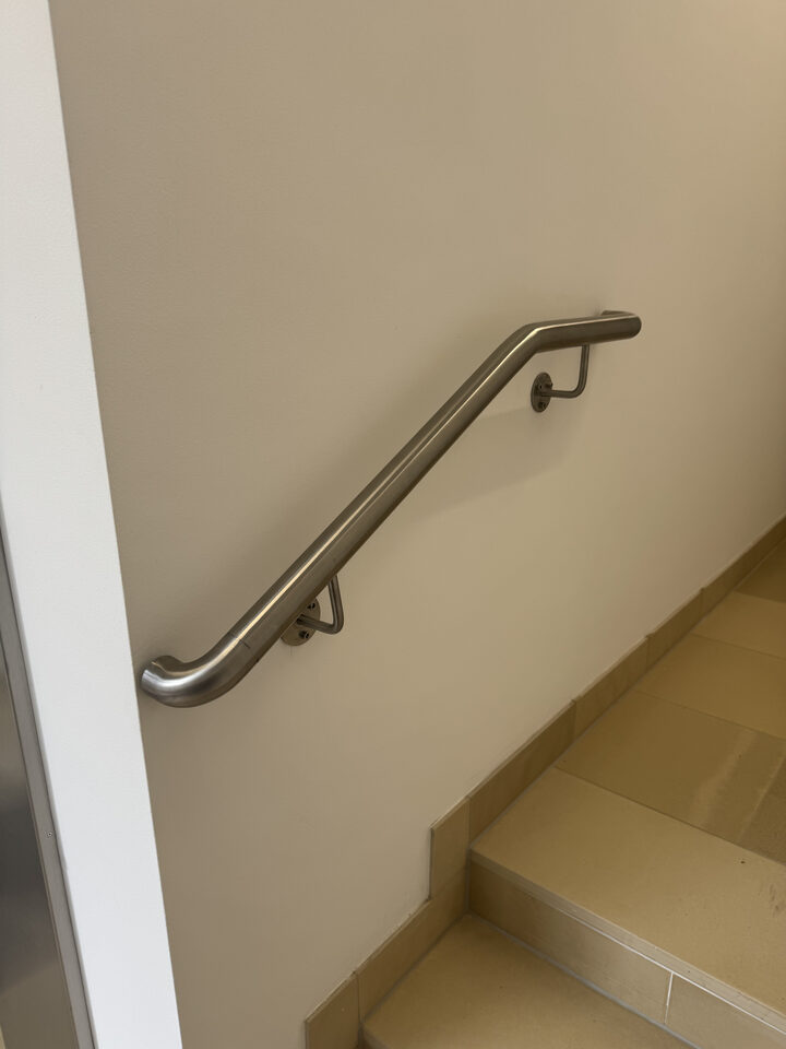 Gebogener Edelstahlhandlauf an einer Treppenhauswand