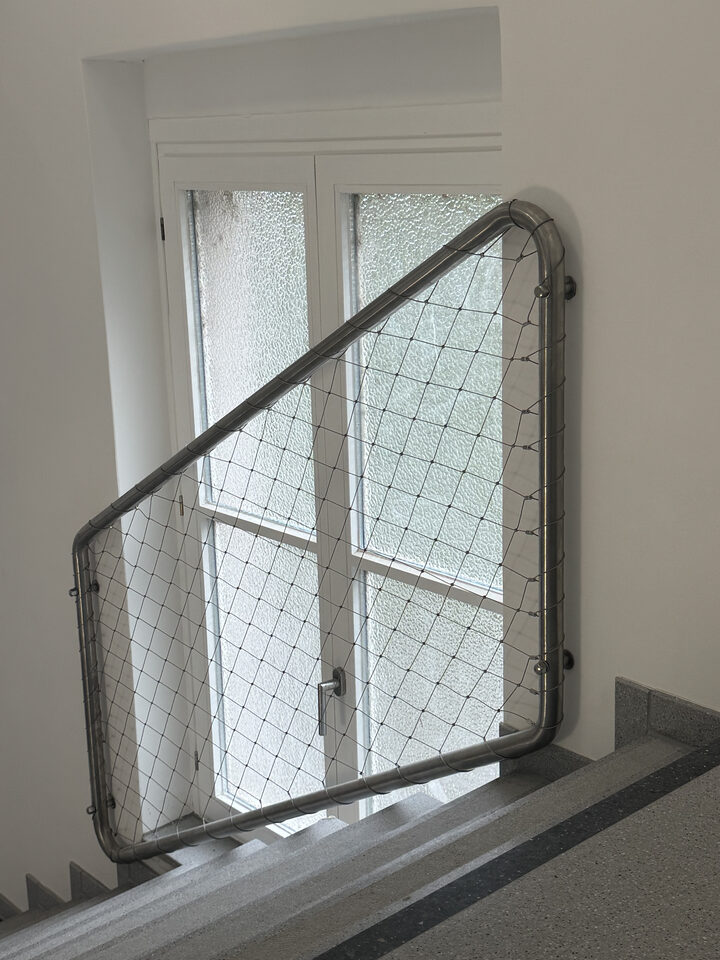 Gebogenes Gitter mit Drahtfüllung über einem Treppenlauf